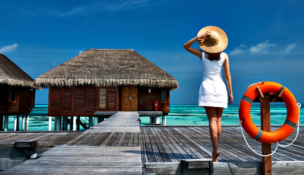 Traveller taking in tropical island villa vistas across ocean waves